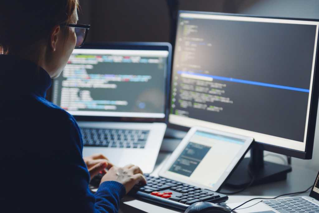 I started ‘vibe coding’ my own apps with AI and I’m utterly loving it Woman in glasses coding with laptop monitor and tablet