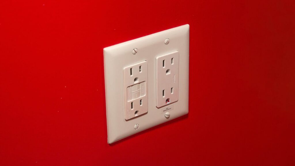 Home electrical outlet with four plugs, in a red wall