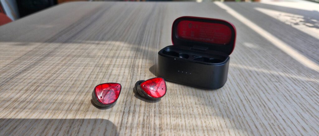 Noble FoKus Amadeus wireless ANC earbuds, and case, on a wooden surface