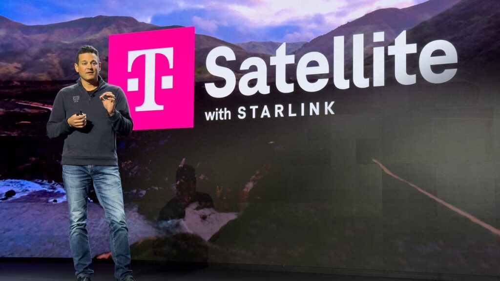 Man on stage speaking with a large screen behind him with information about the T-Satellite feature