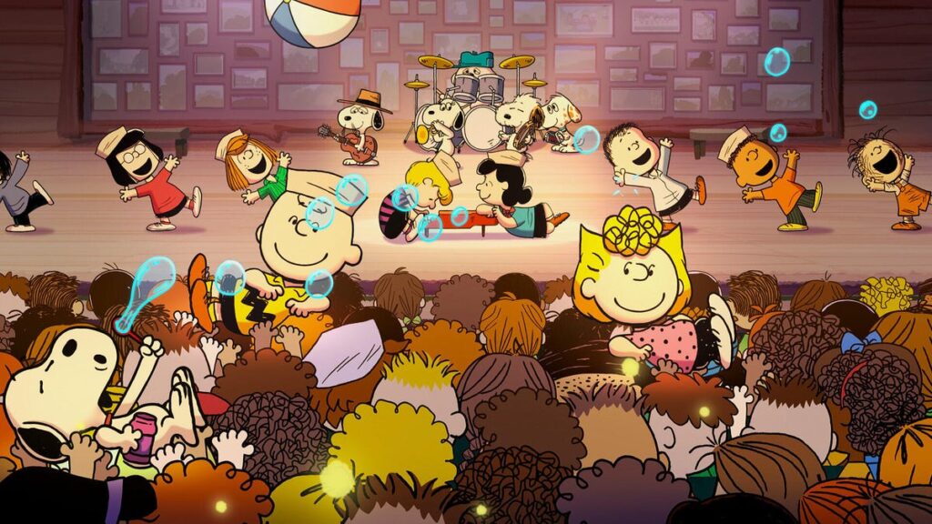 Animated characters from "Peanuts" perform in a musical in front of an audience with Snoopy, Charlie Brown and Lucy.