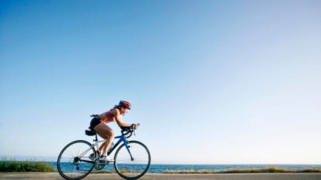 person riding a racing bicycle fast on a dirt path along the water