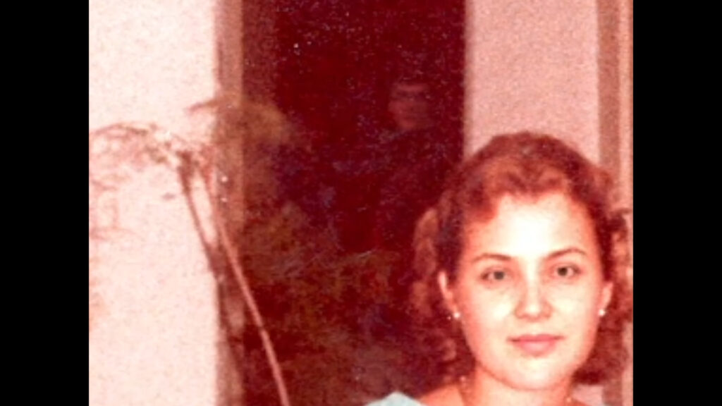 An old photo of a woman with a shadowy figure behind her