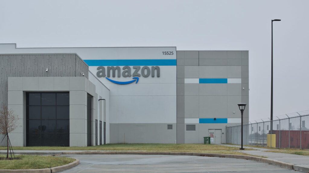 a large, gray Amazon warehouse sits in front of a gray sky