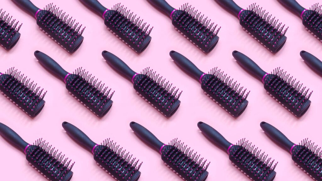 An image of multiple hairbrushes on a pink background (gettyimages-1450804398)