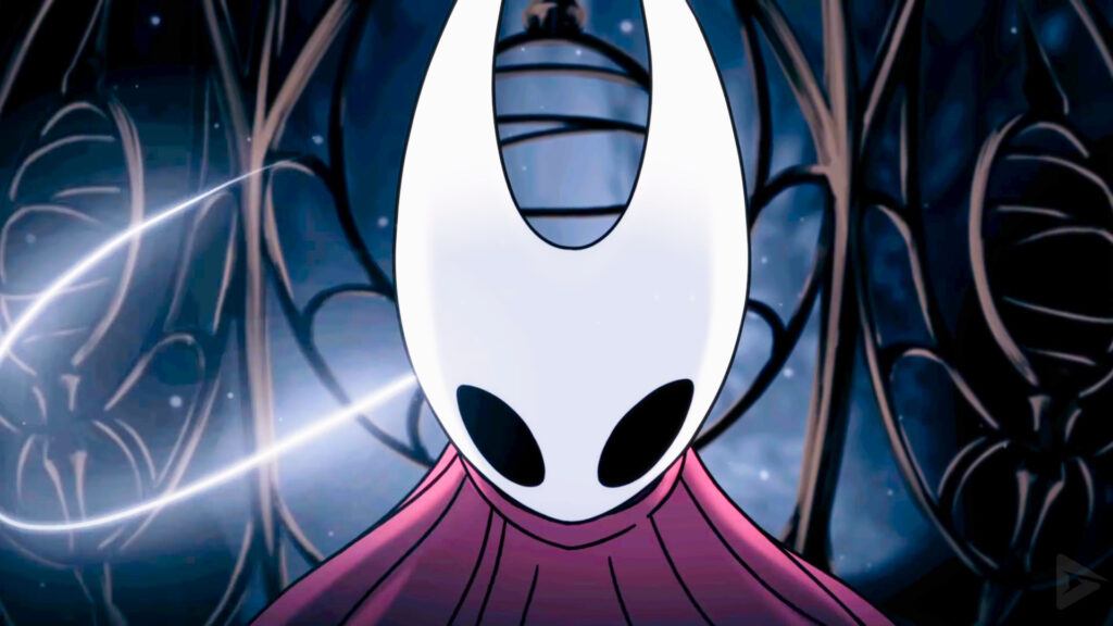 A screencap of Hollow Knight: Silksong's opening cutscene. A close-up shot of protagonist Hornet moments before she breaks out of a metal cage. Her curved white mask and red cloak are lit up as a glowing strand of silk surrounds her.