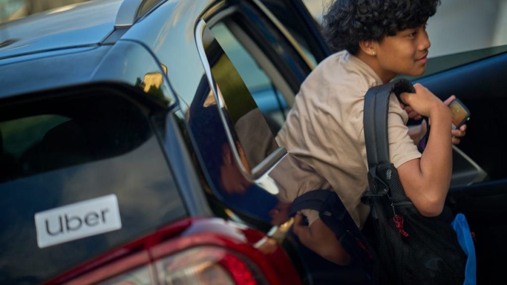 A teenager exits an Uber ride
