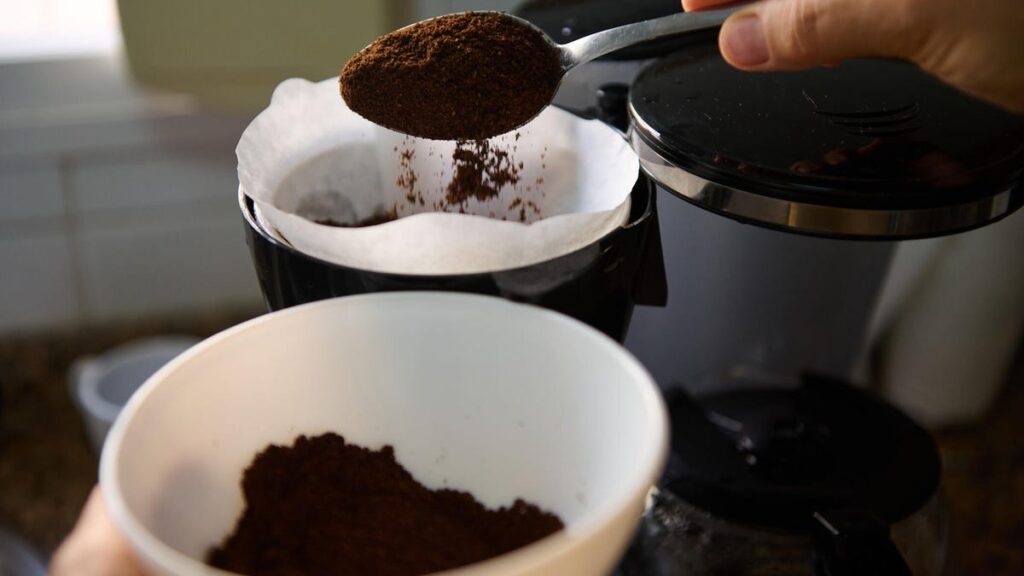 coffee grounds being scooped into filter