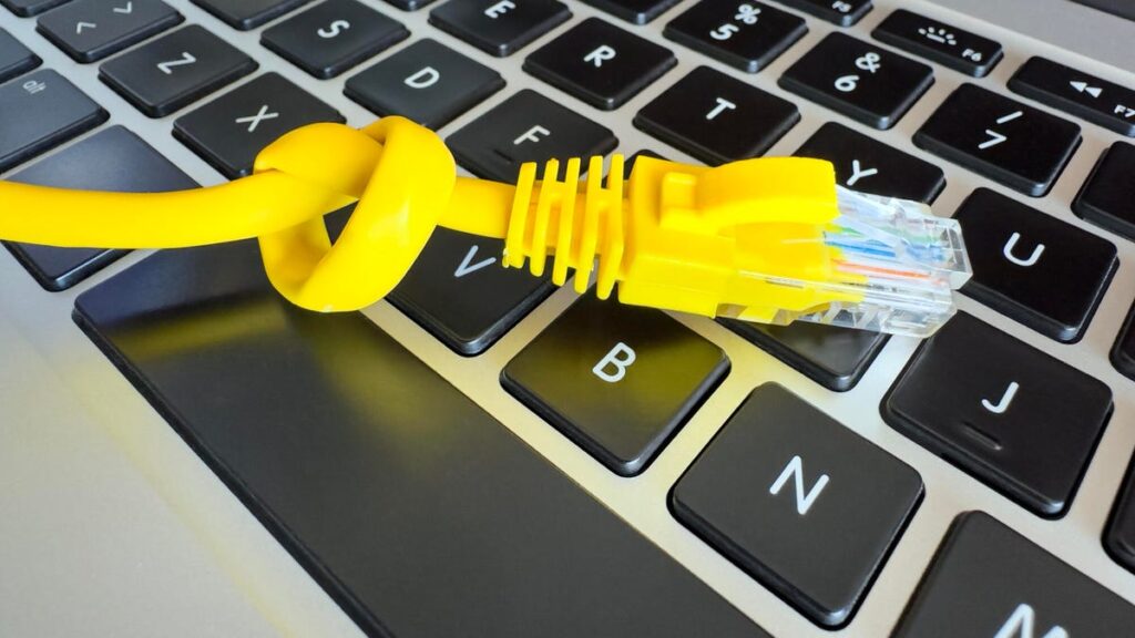 An Ethernet cable tied in a knot, lying on a laptop keyboard