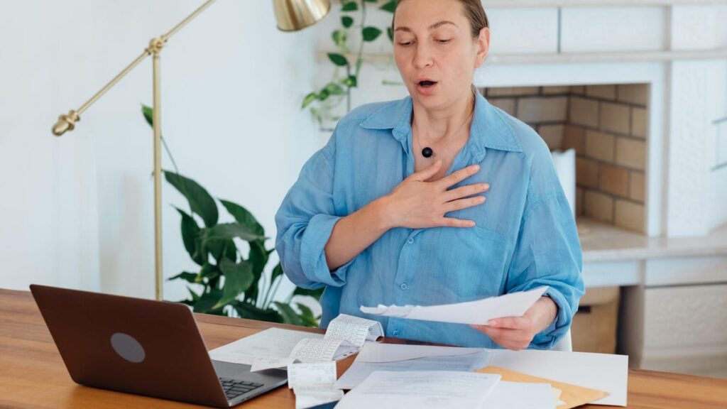 Go Ahead and Let Out a Deep Sigh Right Now. It’s Actually Good for You A woman at a desk letting out a deep sigh.