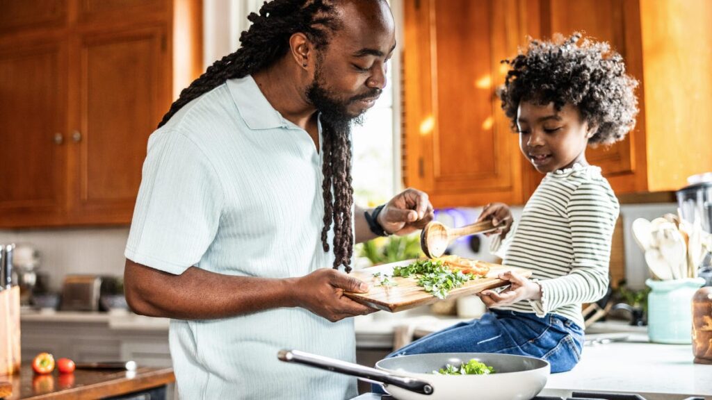 A father and child cooking a meal together in a kitchen.
