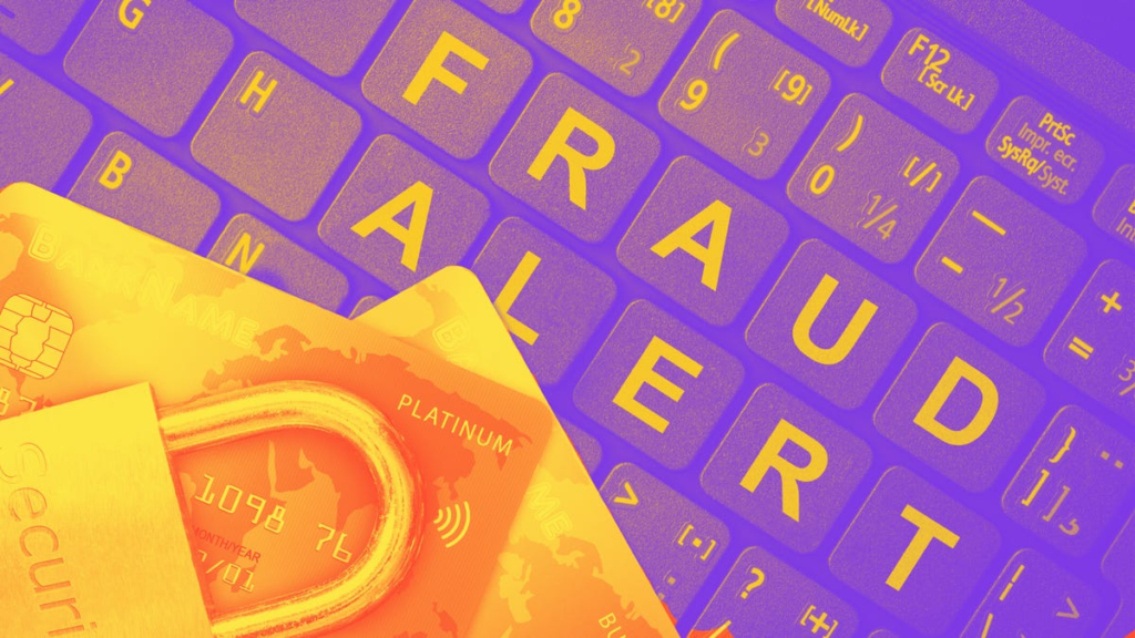 A lock and two credit cards sit on a keyboard that spells out FRAUD ALERT.