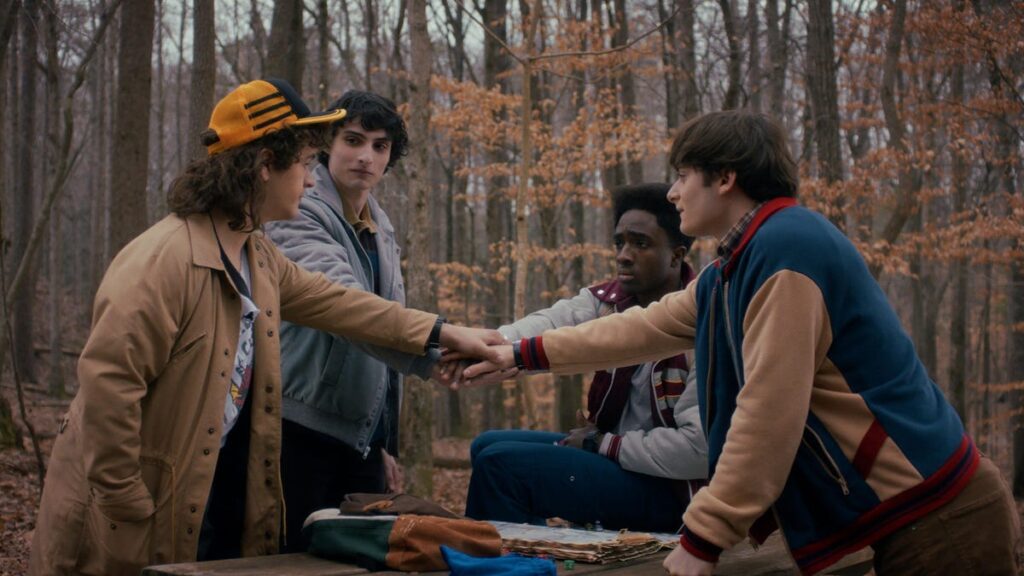 ‘Stranger Things 5’ Finale Episode Will Hit Theaters as a Fan Event 4 teen boys huddle together in the woods