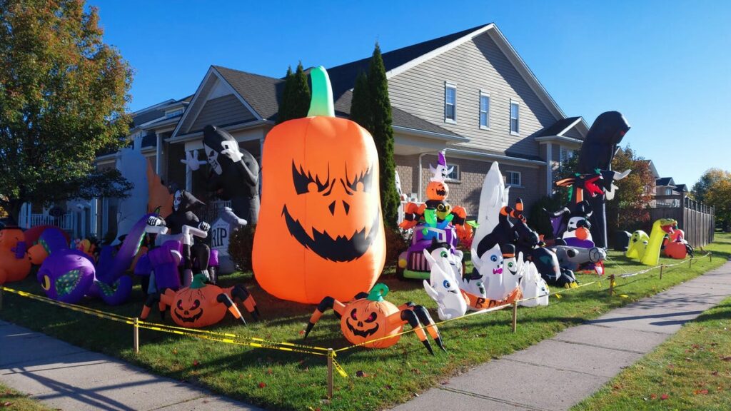 Inflatable Halloween decorations crowd a home lawn behind security tape.